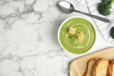 Delicious broccoli cream soup with croutons served on white marble table, flat lay. Space for text