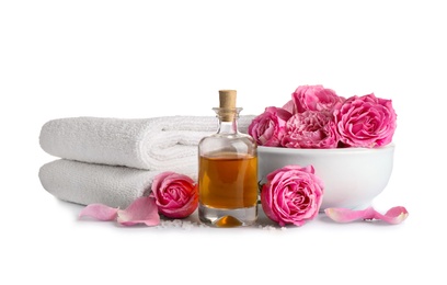 Spa composition with oil, pink flowers and towels on white background