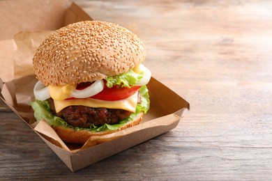 Delicious burger in cardboard box on wooden table