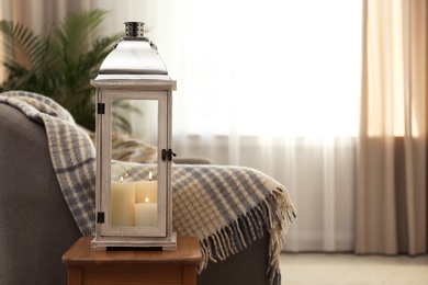 Decorative lantern with candles in living room interior. Space for text