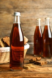 Photo of Bottle of delicious fresh kvass, spikelets and bread on wooden table