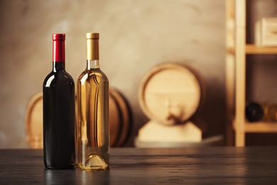 Bottles of delicious wine and blurred barrels on background