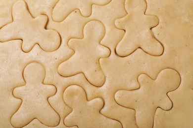 Making homemade Christmas cookies. Raw dough with gingerbread men shapes as background, top view