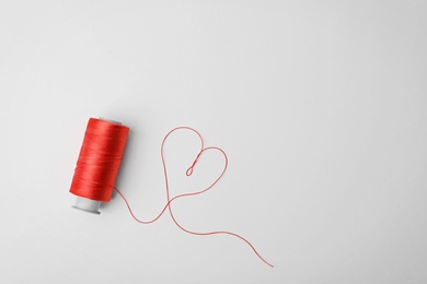 Heart made of color sewing thread and spool on white background, top view
