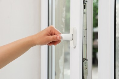 Woman opening white plastic window at home, closeup