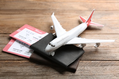 Toy airplane and passports with tickets on wooden background
