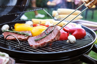 Barbecue grill with meat and vegetables outdoors, closeup