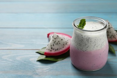 Delicious pitahaya smoothie, fruit and fresh mint on light blue wooden table, space for text