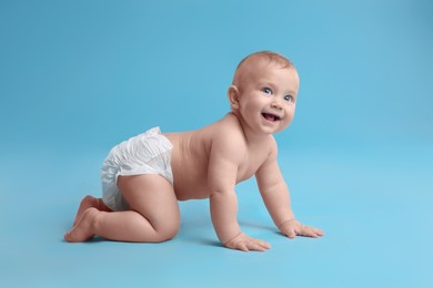 Cute baby in dry soft diaper crawling on light blue background