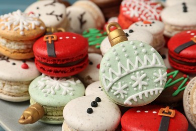Photo of Beautifully decorated Christmas macarons on plate, closeup