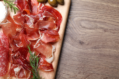 Tasty prosciutto served on wooden table, top view. Space for text