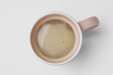 Mug of freshly brewed hot coffee on white background, top view
