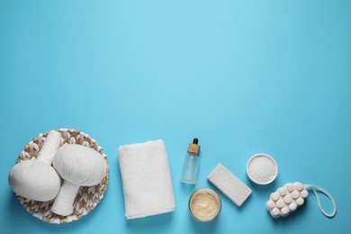 Beautiful spa composition with herbal massage bags and different care products on light blue background, flat lay. Space for text