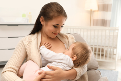 Photo of Woman breastfeeding her little baby at home