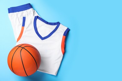 Basketball uniform and ball on light blue background, flat lay. Space for text