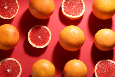Cut and whole ripe grapefruits on red background, flat lay