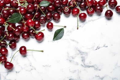 Sweet juicy cherries on white marble table, flat lay. Space for text