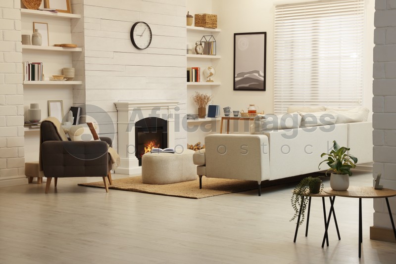 Stylish living room interior with comfortable sofa and decorative fireplace