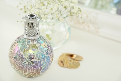 Closeup view of stylish catalytic lamp with beautiful gypsophila and earrings on white table, space for text. Cozy interior