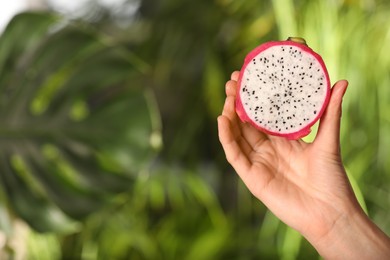 Photo of Woman holding fresh cut dragon fruit (pitahaya) on blurred background, closeup. Space for text