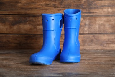 Bright blue rubber boots on wooden surface