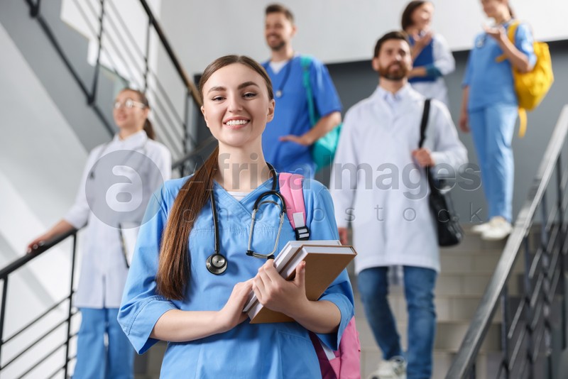 Portrait of medical student with books on staircase in college, space for text