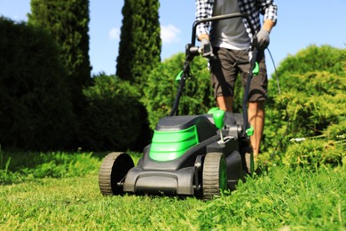 Photo of Man turning on lawn mower in garden, closeup. Cutting grass
