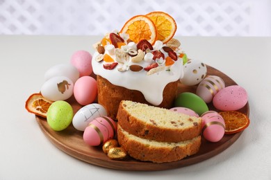 Photo of Traditional Easter cake with dried fruits and decorated eggs on white table