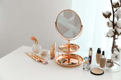 Small mirror and different makeup products on table indoors