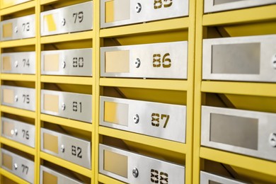 Many closed metal mailboxes with keyholes and numbers in post office, closeup
