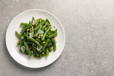 Plate of tasty salad with green beans on light grey table, top view. Space for text