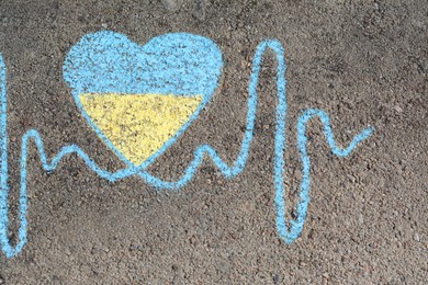 Cardiogram line with heart drawn by blue and yellow chalk on asphalt, top view