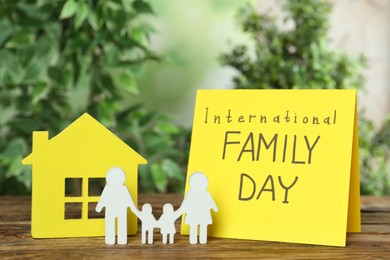 Card with text International Family Day and figures on wooden table