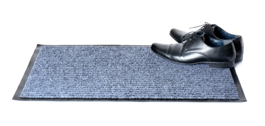 Black classic shoes on gray doormat against white background