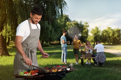 Man cooking meat and vegetables on barbecue grill in park