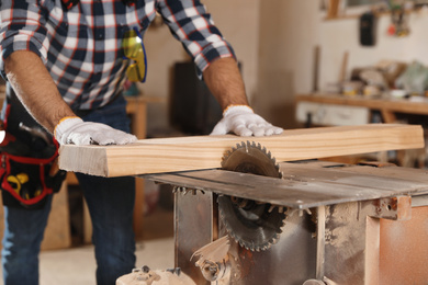 Professional carpenter working with sawmill machine in workshop, closeup