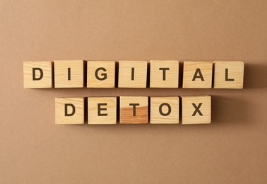 Photo of Wooden cubes with phrase DIGITAL DETOX on brown background, flat lay