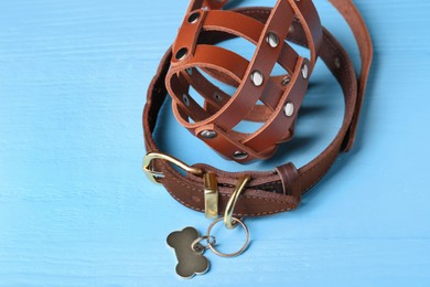 Photo of Brown leather dog muzzle and collar on light blue wooden table