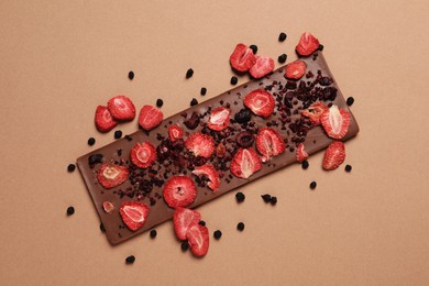 Photo of Chocolate bar with freeze dried fruits on beige background, top view