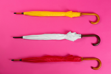Colorful umbrellas on pink background, flat lay