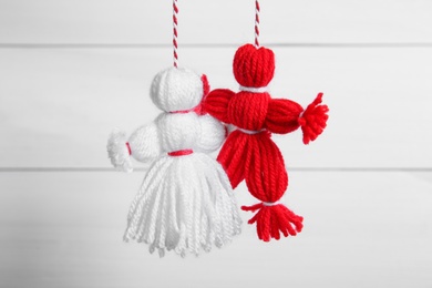 Photo of Traditional martisor shaped as man and woman on white wooden background. Beginning of spring celebration