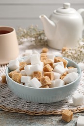 Photo of Different refined sugar cubes in bowl on rustic table