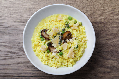 Photo of Delicious risotto with cheese and mushrooms on wooden table, top view