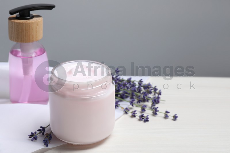 Photo of Jar of hand cream, cosmetic product and lavender on white wooden table, space for text
