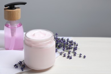 Jar of hand cream, cosmetic product and lavender on white wooden table, space for text