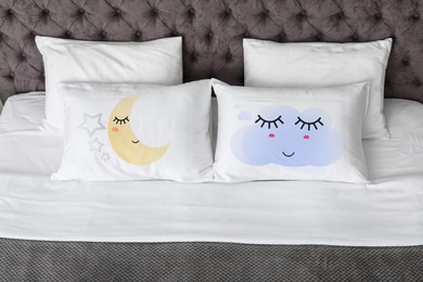 Soft pillows with cute faces on comfortable bed 