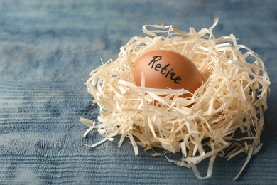 Egg with word RETIRE in nest on wooden background. Pension concept