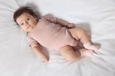 Photo of Cute little baby on cosy bed, top view