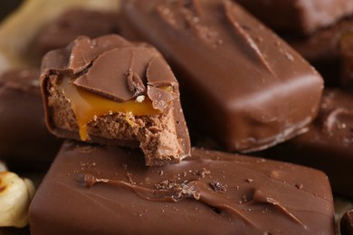 Many tasty chocolate bars with caramel as background, closeup