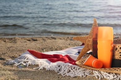 Sun protection products, hat and starfish on blanket near sea, space for text